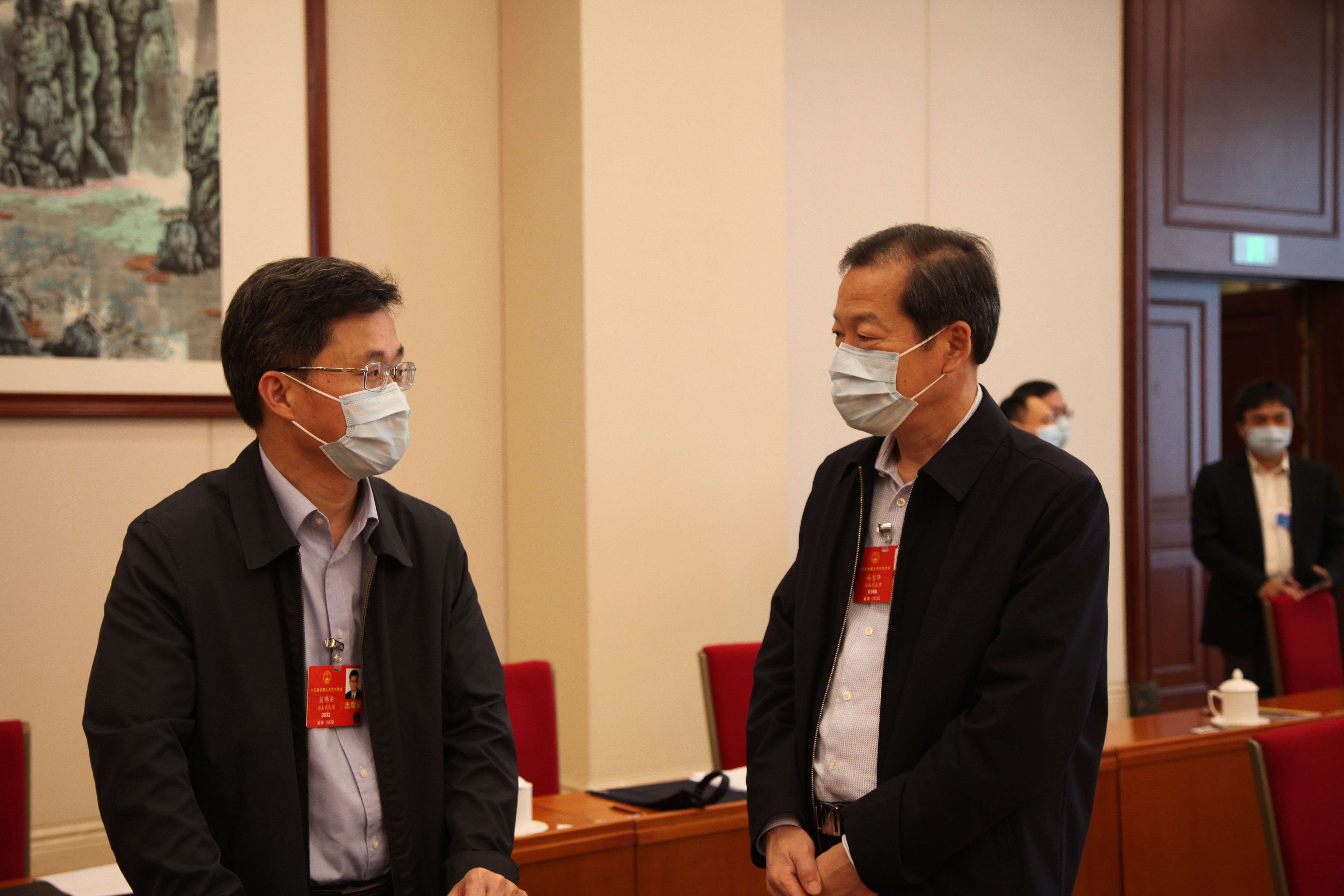 5月24日，海南代表团审查计划报告和预算报告，图为会议间隙，蓝佛安代表与冯忠华代表交流讨论。张旭图