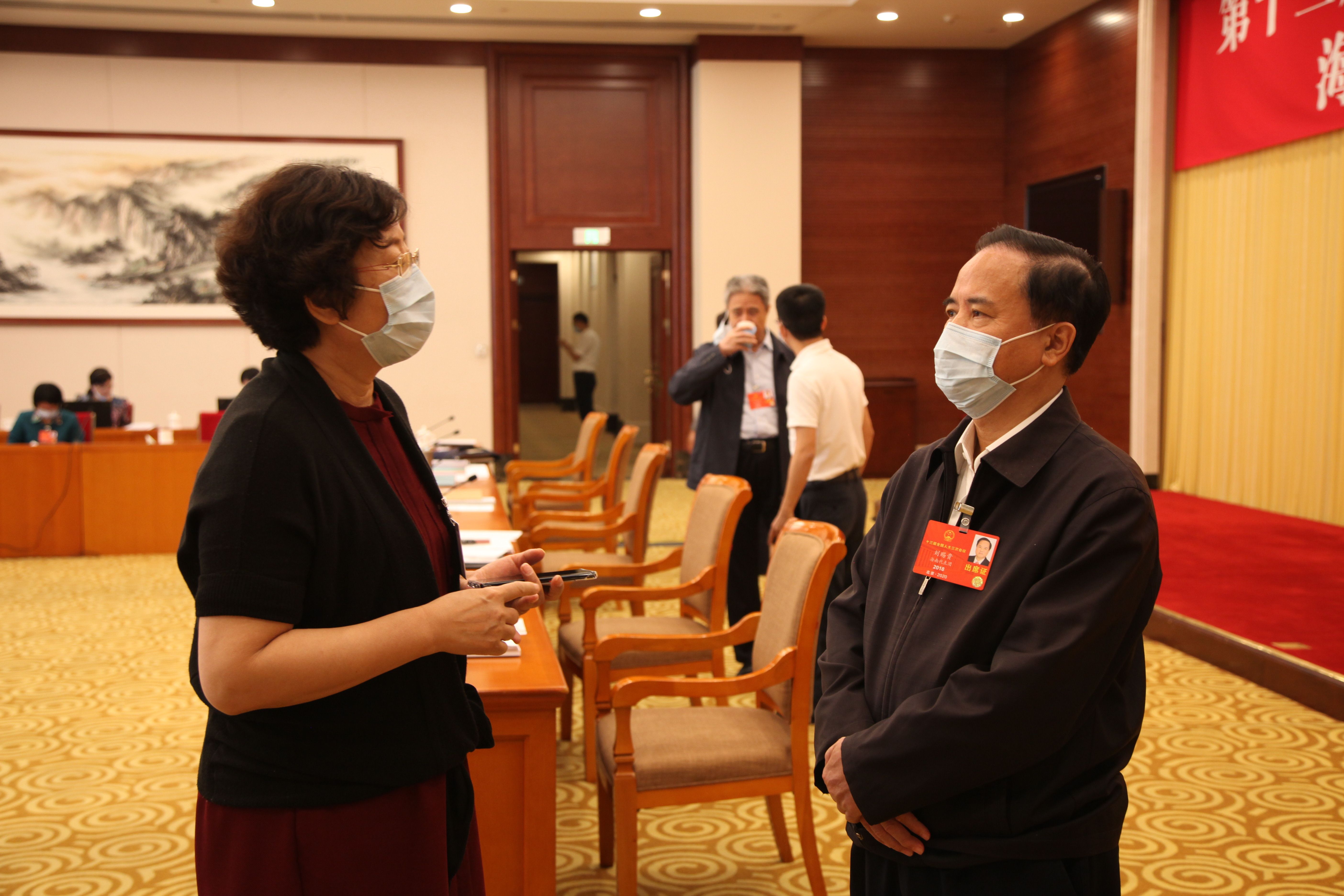 5月24日，海南代表团审查计划报告和预算报告，图为会议间隙，刘赐贵代表和吕彩霞代表交流讨论。张旭图